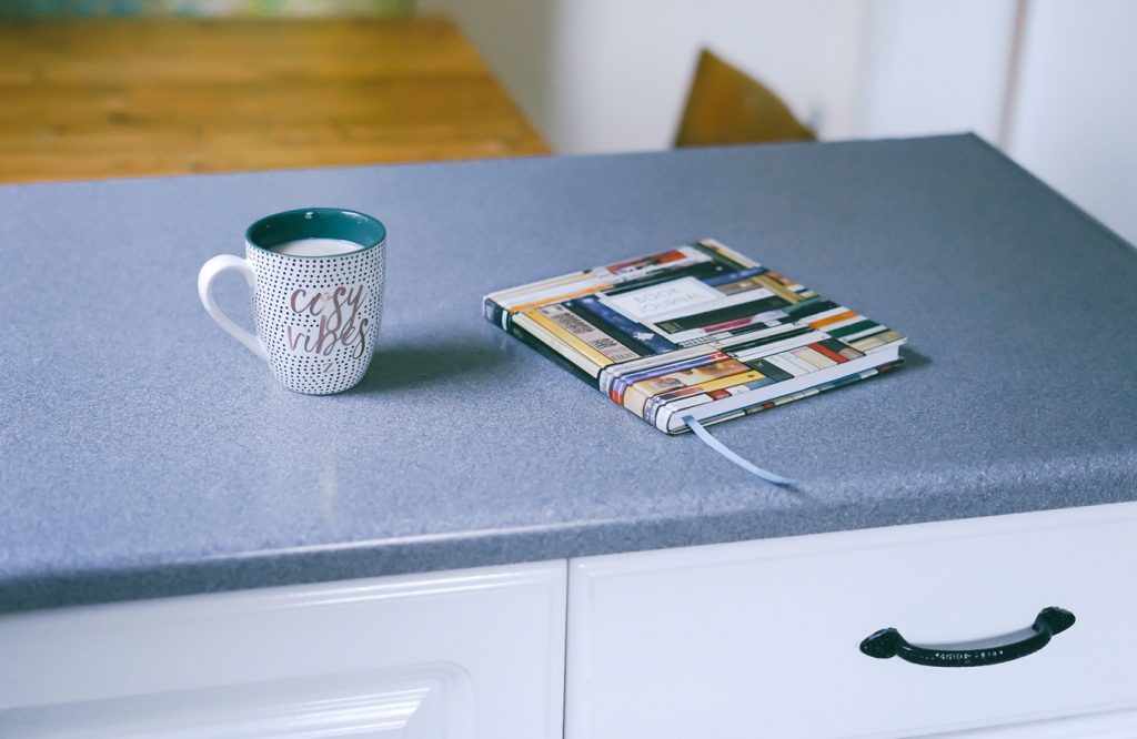 A mug and a book sit on top of a finished countertop.