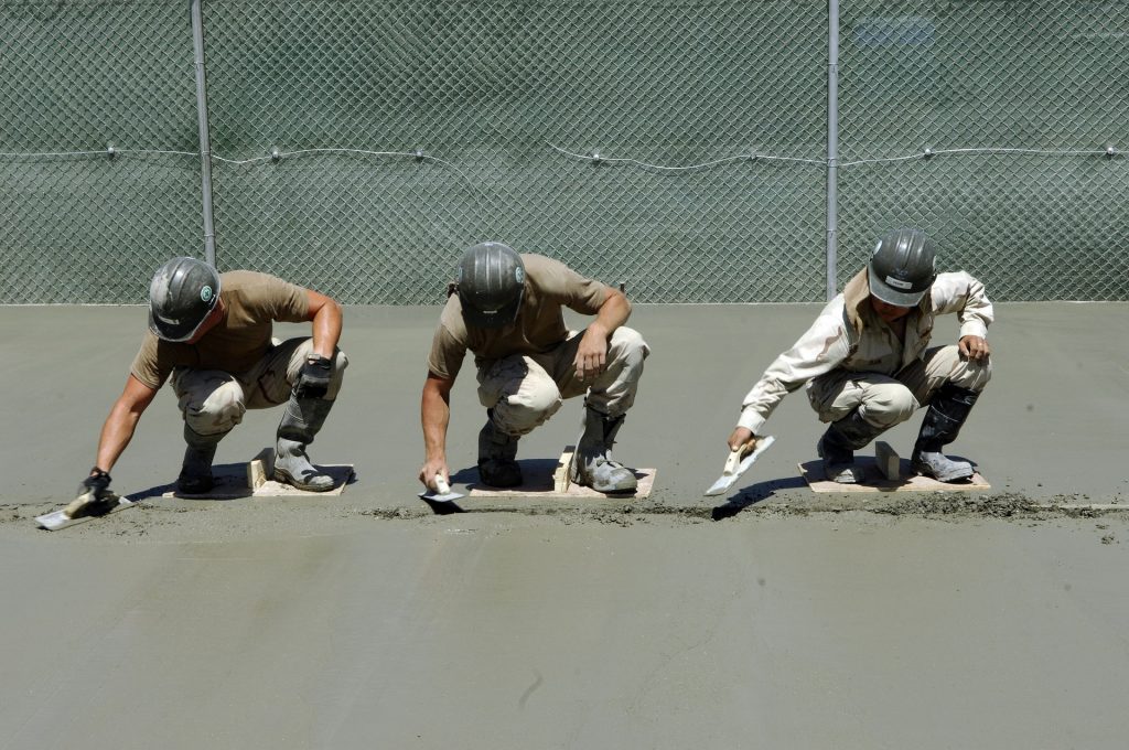 Three men lay concrete outside