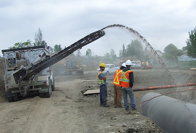 Construction workers using a stone slinger to transfer stone